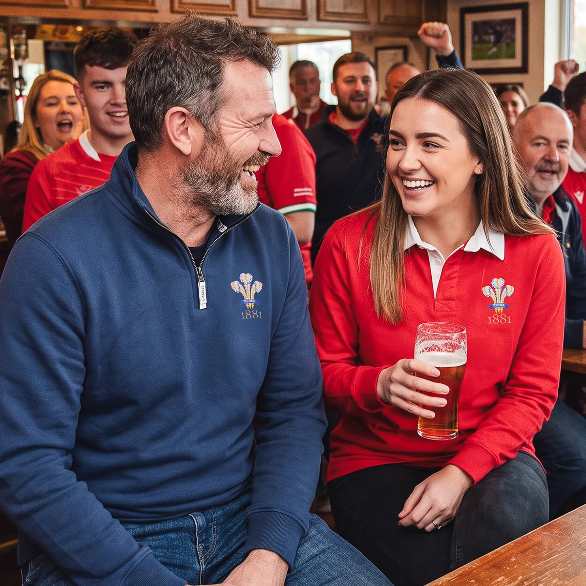 A father and his daughter sit enjoying a drink in a rugby clubhouse after a rugby match. They are both wearing products from the R1823 Wales 1881 collection.